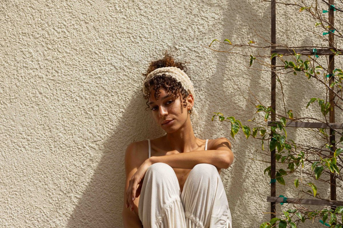 A person sitting on a bench against a warm stucco wall.