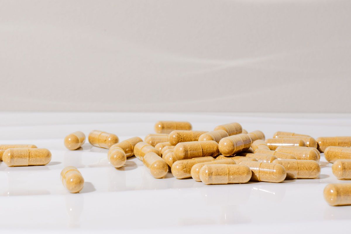 A scatter of tan mushroom capsules on a pale surface.