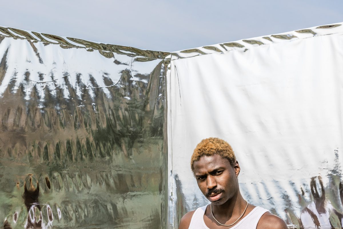 A man holding a jar of Ritual Therapy in front of hanging fabric.