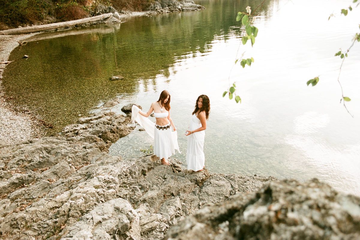 Two people wading in shallow green lake water in soft daylight.