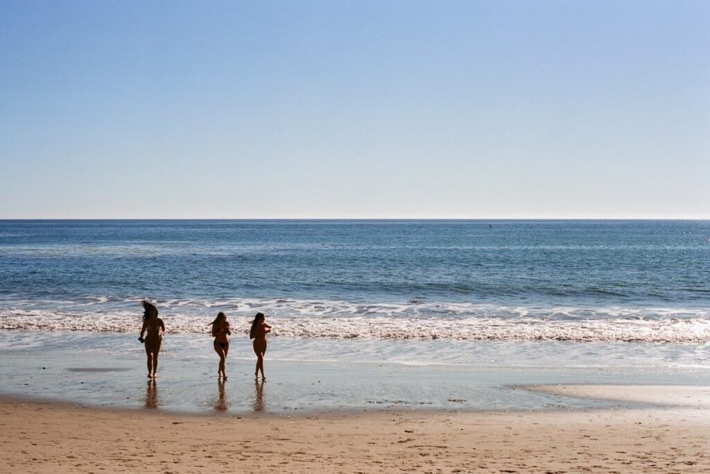 Three friends at the edge of the water on a wide open beach