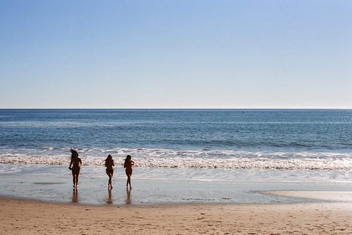 Three friends at the edge of the water on a wide open beach