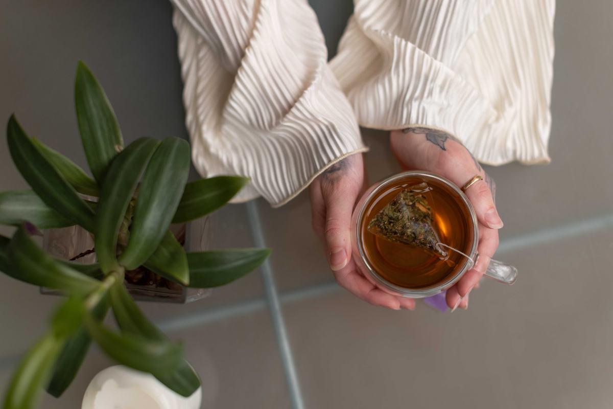 Two hands cradling a glass mug of Mycrologi Longevity Tea